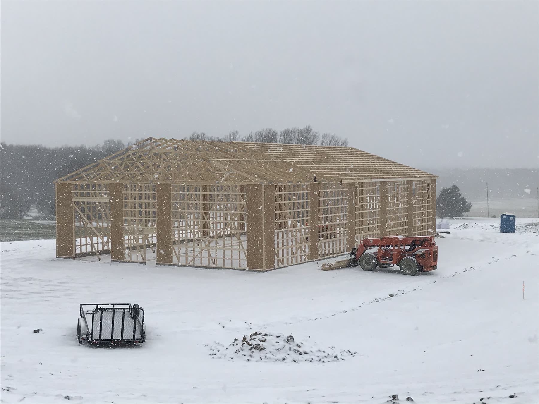 Wood-framed equipment storage building under construction in the snow