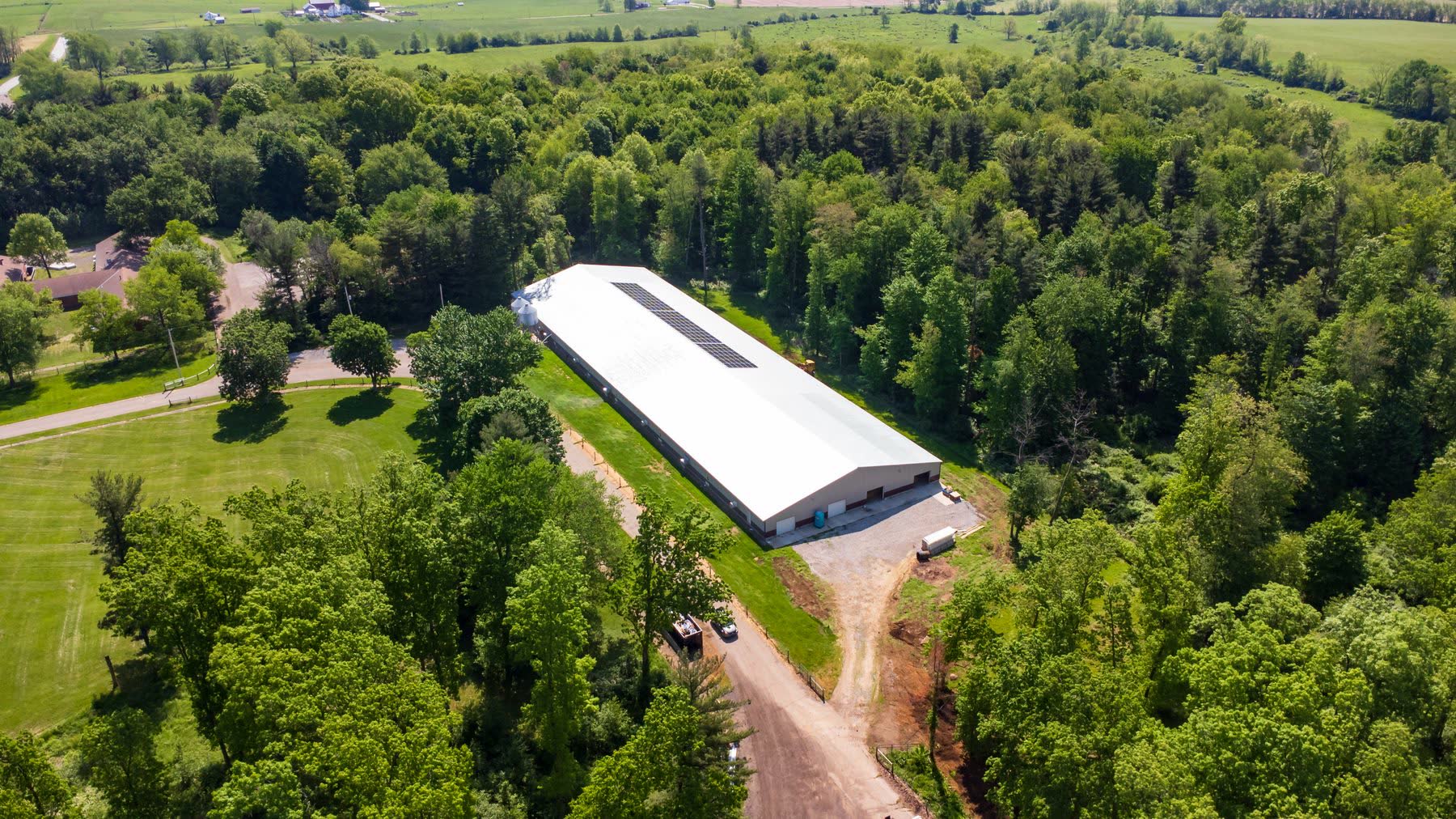 Aerial view of a large agricultural building with a metal roof and solar panels on rural Ohio acreage