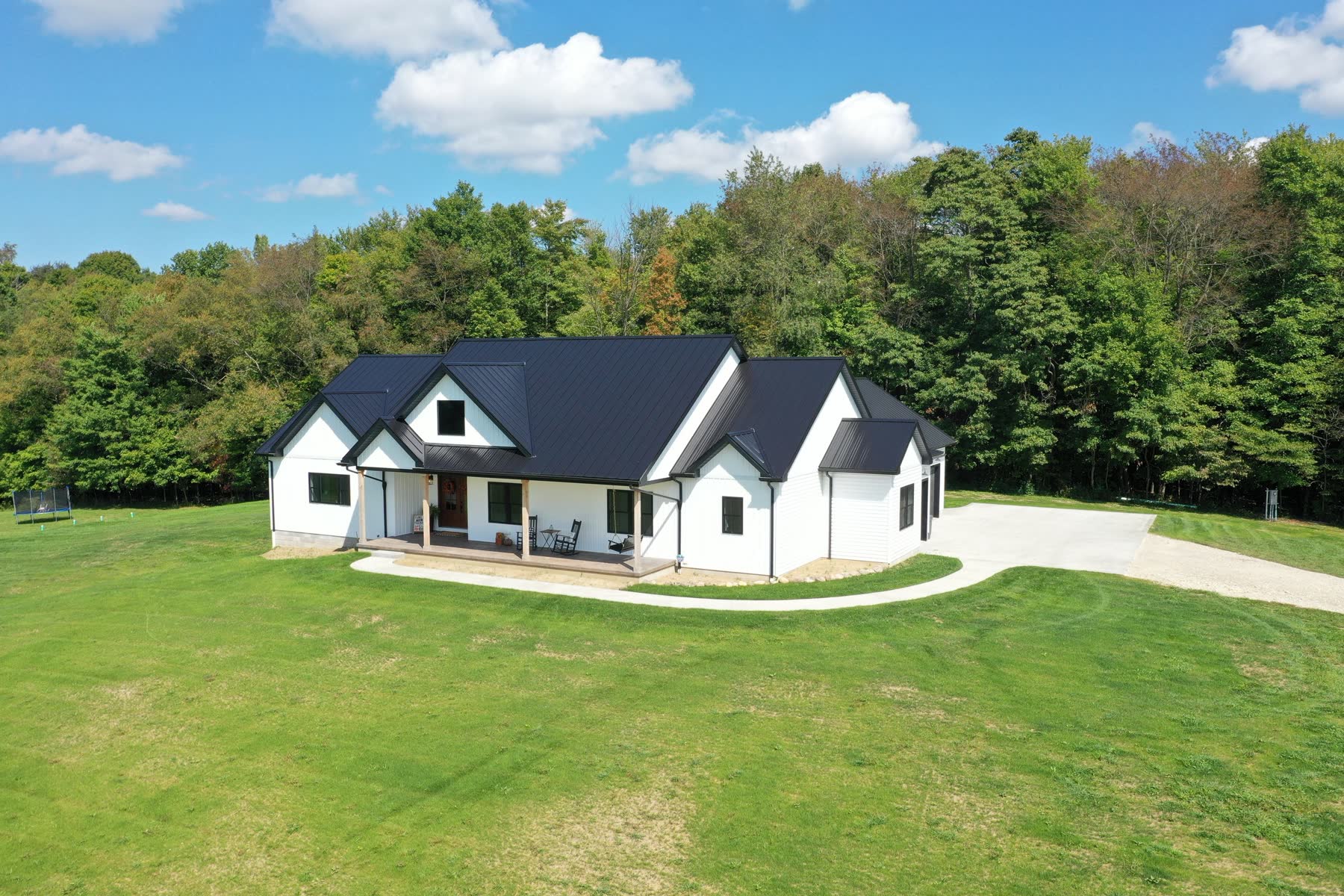 Finished white farmhouse-style custom home with a wraparound porch