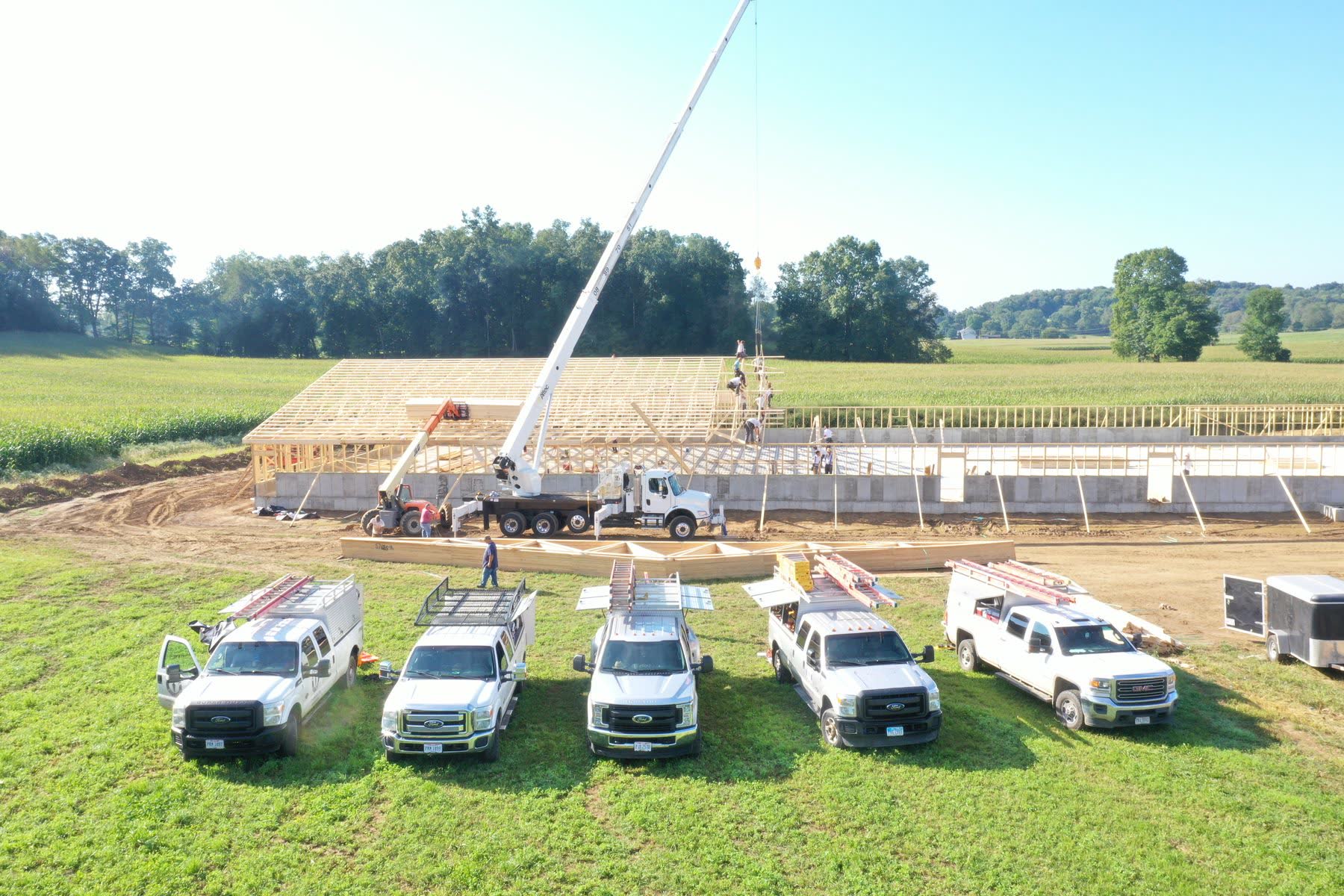 Avodah crew trucks and equipment lined up on a rural jobsite during framing