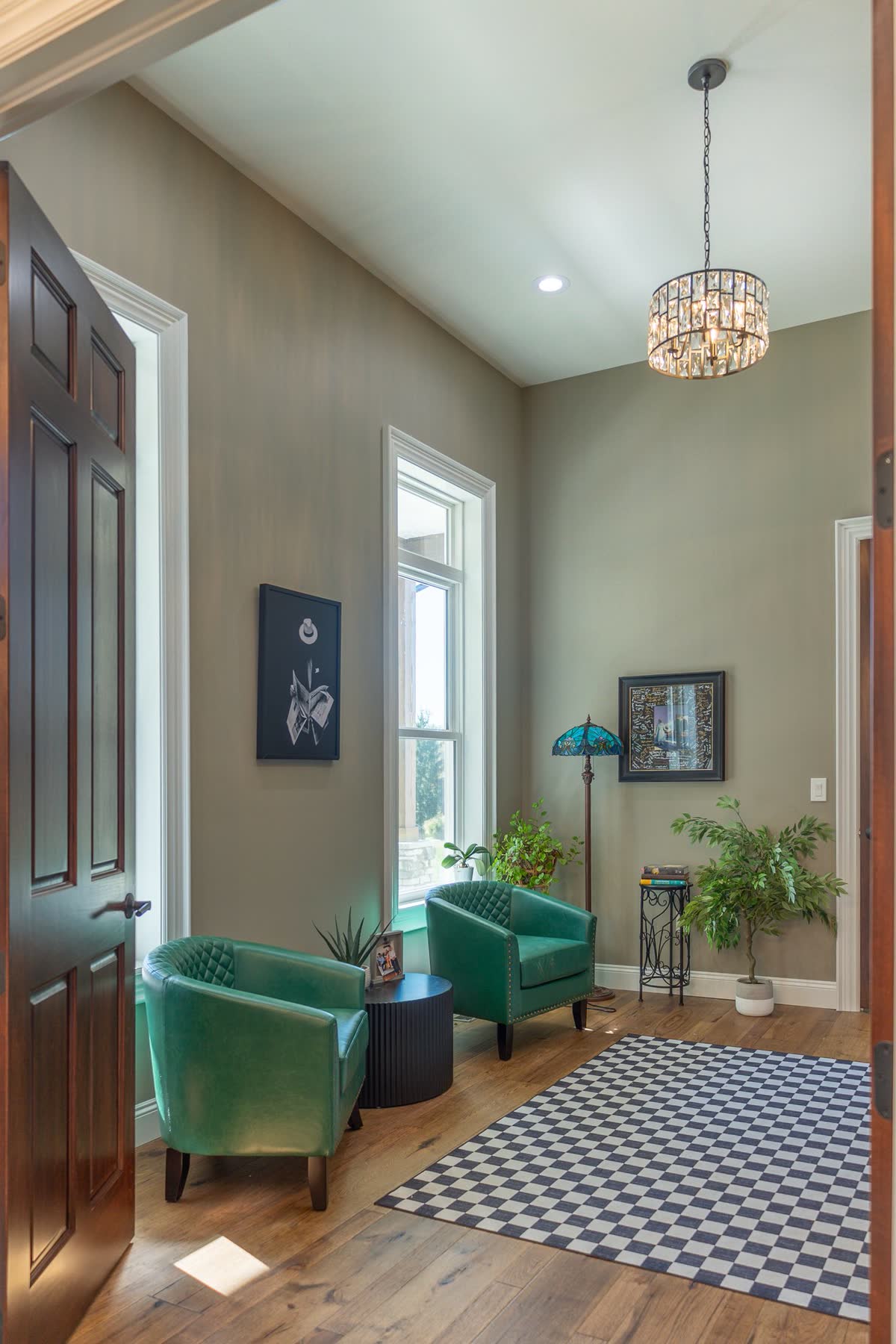 Entry sitting area with green leather chairs and crystal pendant