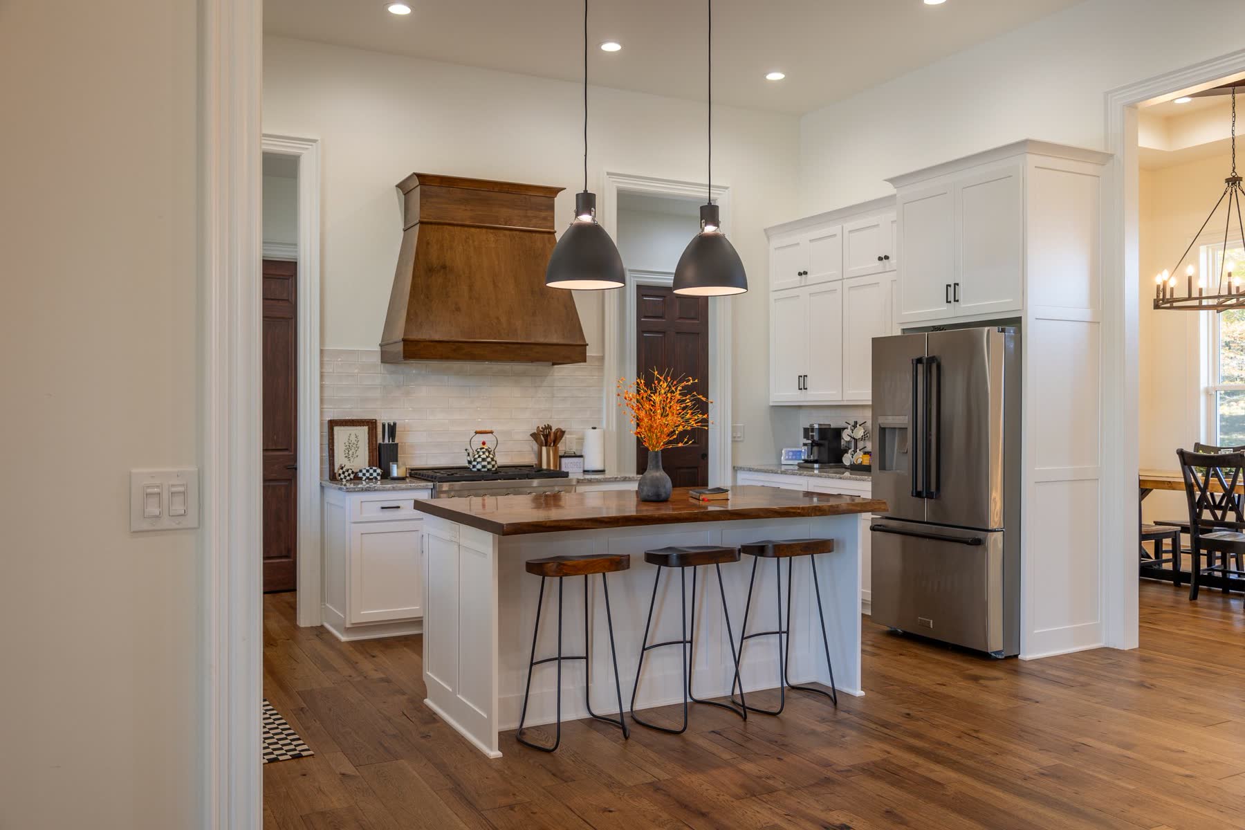 Custom kitchen with wood island, range hood, and pendant lighting
