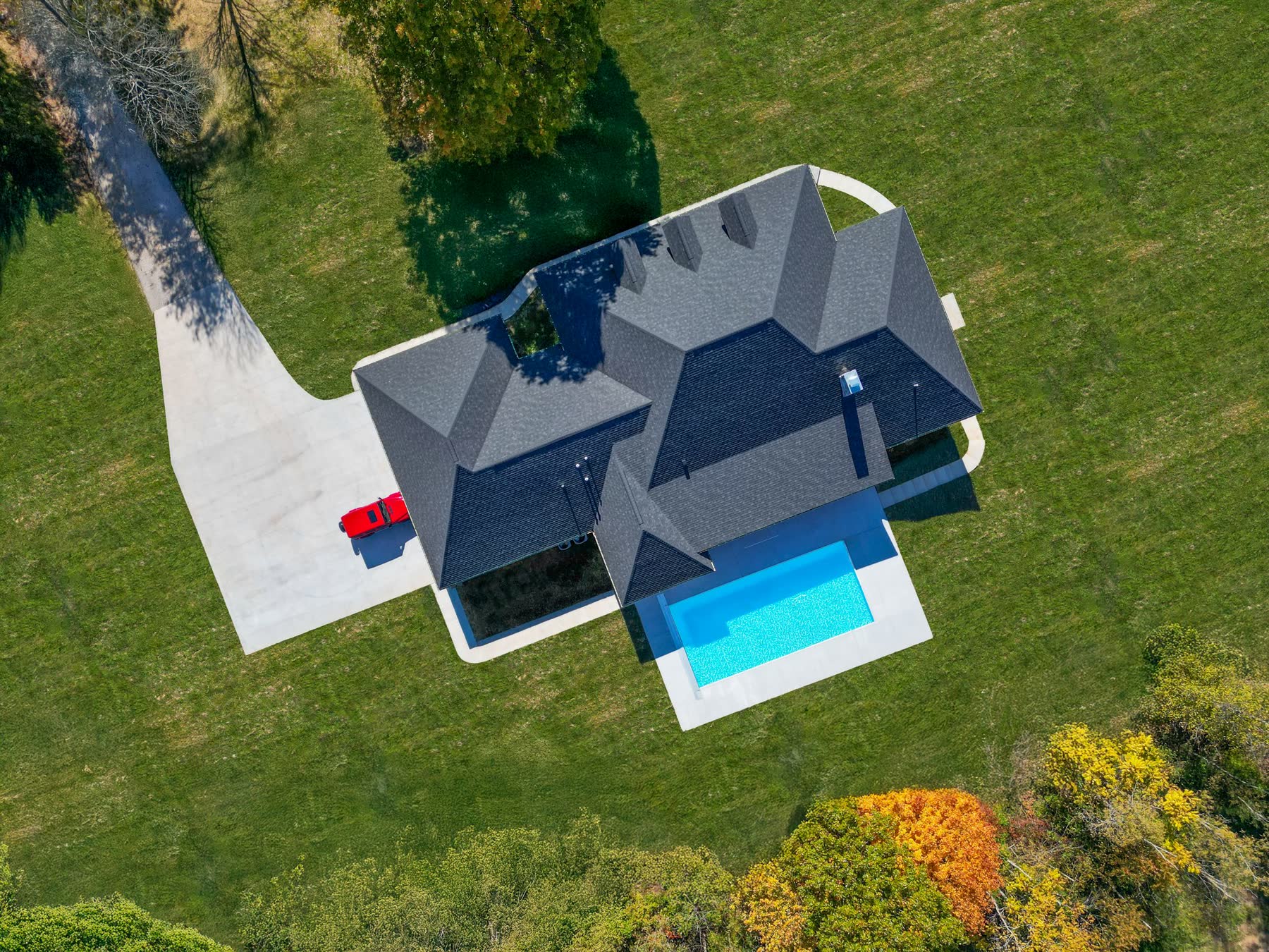 Aerial view of a custom-built home with pool and three-car driveway