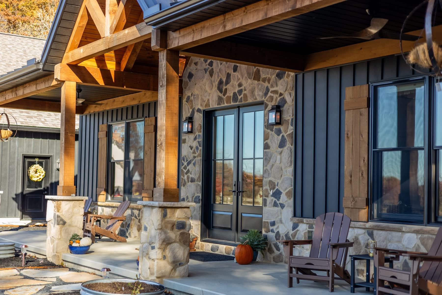 Covered front entry of a finished Avodah custom home with stone accents and timber-frame porch