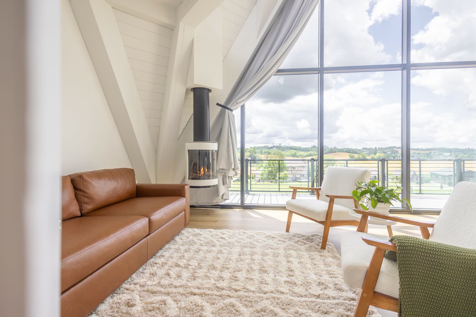 A-frame rental living area with wood stove and floor-to-ceiling windows