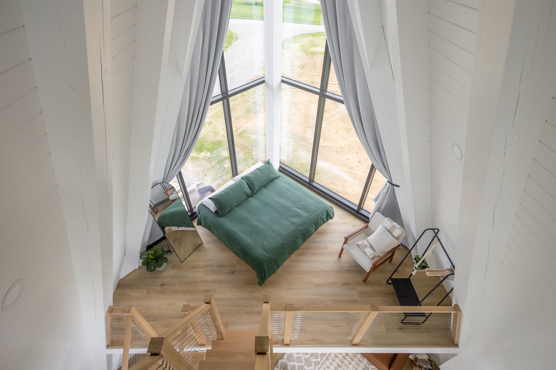 Overhead view of an A-frame loft bedroom with green bedding