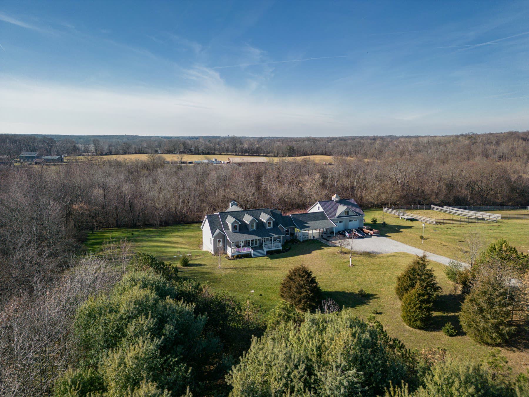 Custom-built farmhouse-style residence on acreage with attached garage and fenced paddock