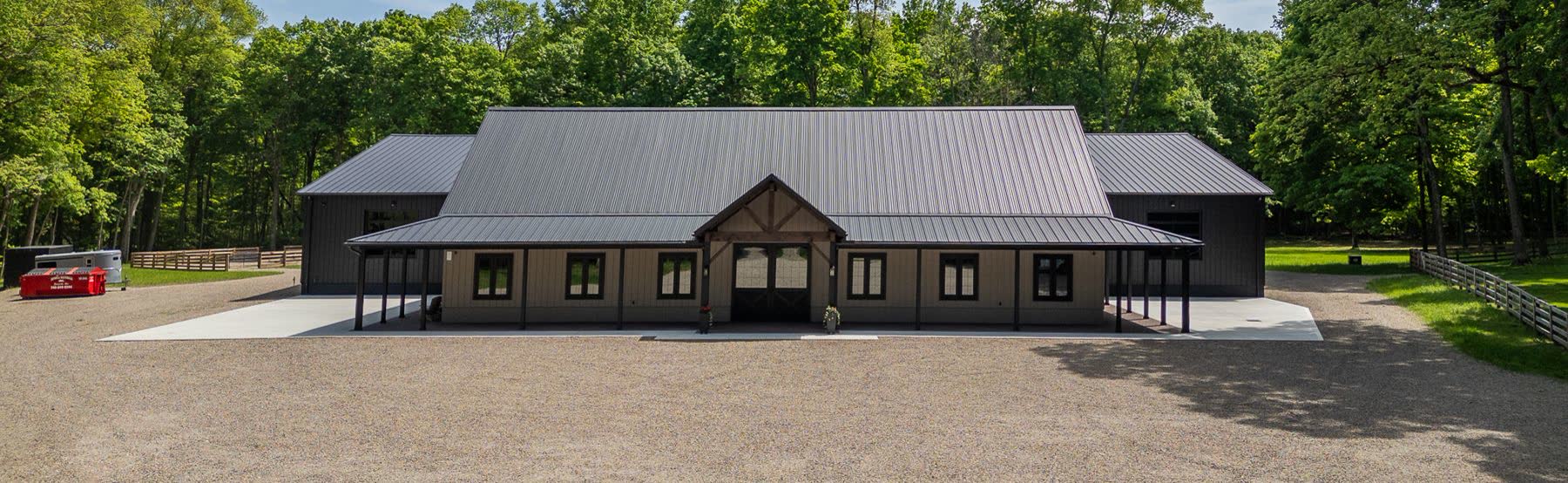 Dark-sided private barn with a timber-framed entry and gravel drive