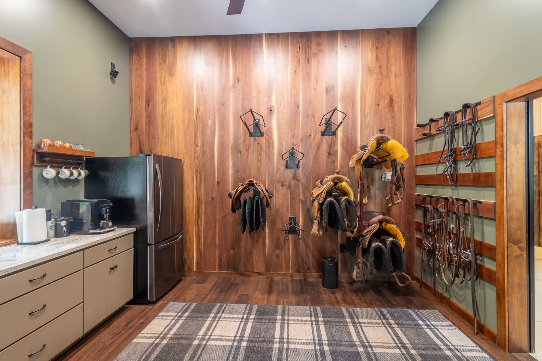 Tack room with saddles and bridles on a walnut-paneled wall