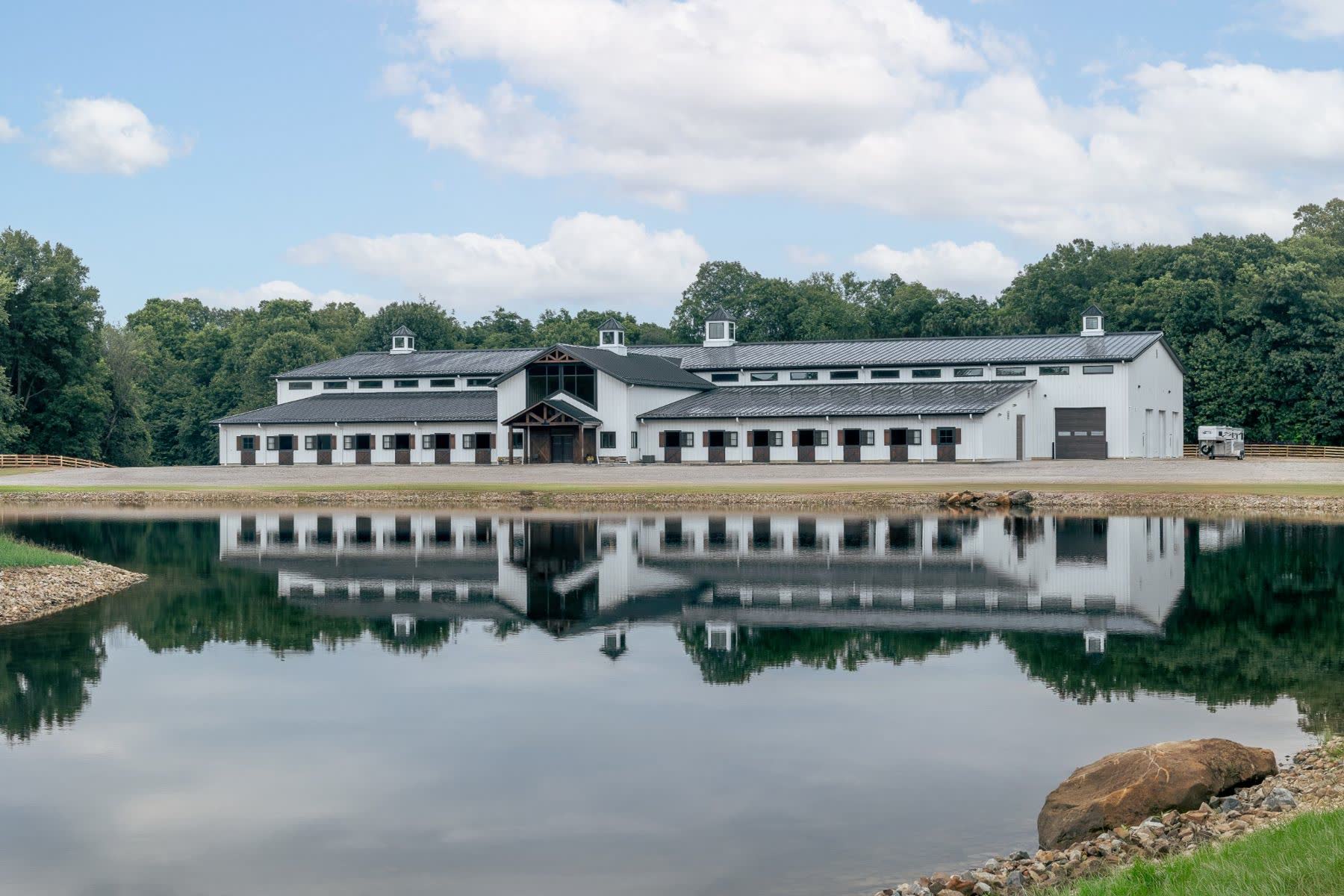 White Woodland Acres equestrian facility with cupolas reflected in a pond