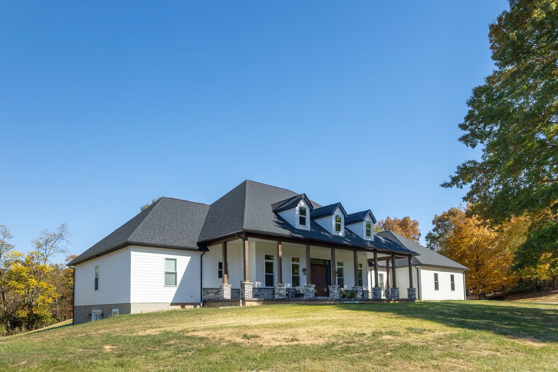 Finished white farmhouse-style custom home with a large front lawn